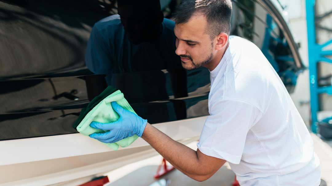 A man cleaning a boat hull with a cloth