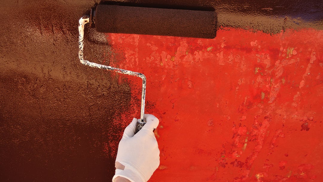 Person reapplying coats of traditional antifouling paint to their boat hull